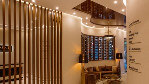 A modern lobby with a wooden partition, a seating area with a sofa and armchairs, a bar area, and a staircase leading to upper floors. - LETO Boutique Hotel (Zugdidi)