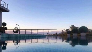 A clear view of a swimming pool with a tiled edge, a rope barrier, and a view of the sky and distant mountains. - LETO Boutique Hotel (Zugdidi)