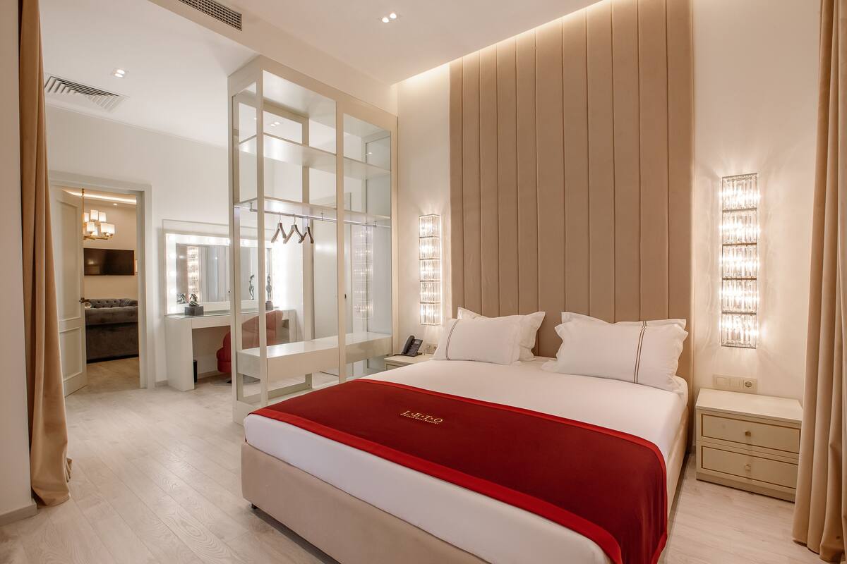 Ein modernes Hotelzimmer mit einem großen Bett, einem Schreibtisch und einem begehbaren Kleiderschrank.