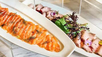 A white rectangular plate with salmon slices garnished with dill, accompanied by a side salad with mixed greens and flowers.