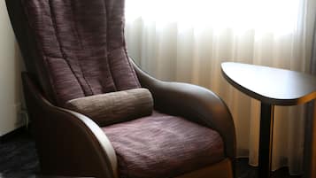 Un sillón moderno con respaldo alto y asiento acolchado, situado junto a una pequeña mesa redonda.