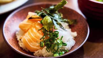 Een schaal sushi met rijst, zalm en garnering.