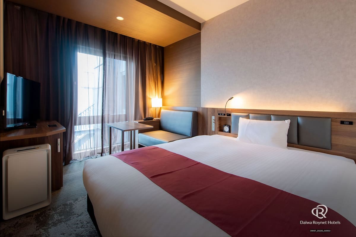 Une chambre d’hôtel avec un grand lit, une télévision, un bureau et une chaise.