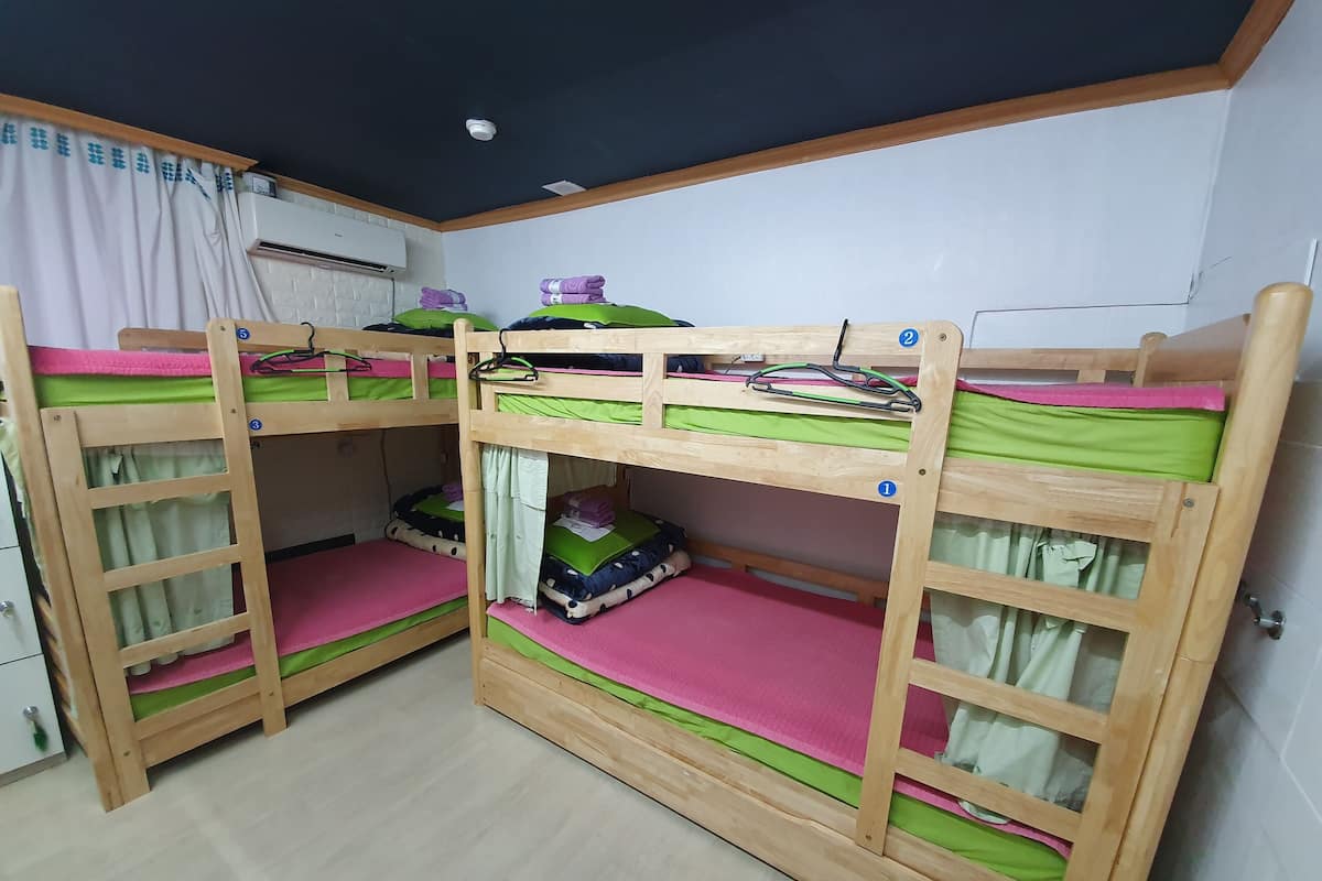 Habitación con literas, un armario blanco, una lámpara de techo y una ventana con cortinas.