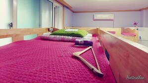 Una habitación con una cama, cabecero de madera, una ventana con persianas, unidad de aire acondicionado y una mesita con un florero.
