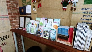 Una exhibición de libros y un certificado sobre una mesa de madera frente a un muro de ladrillo.