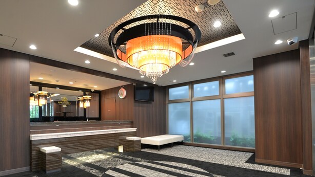 A hotel lobby with a reception desk, a large chandelier, a seating area, and a large window with a view. - APA Hotel Sagamihara Hashimotoeki Higashi (Sagamihara)