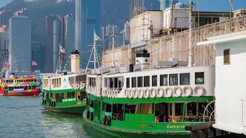 Two green boats docked at a harbor with a city skyline in the background.