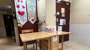 A wooden table with a sign, a chair, and a wall with a door and some signs. - AMU Dreamhouse - Hostel (Kowloon)