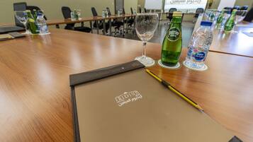 Een vergaderruimte met een houten tafel, waterflesjes, een glas en een laptop.