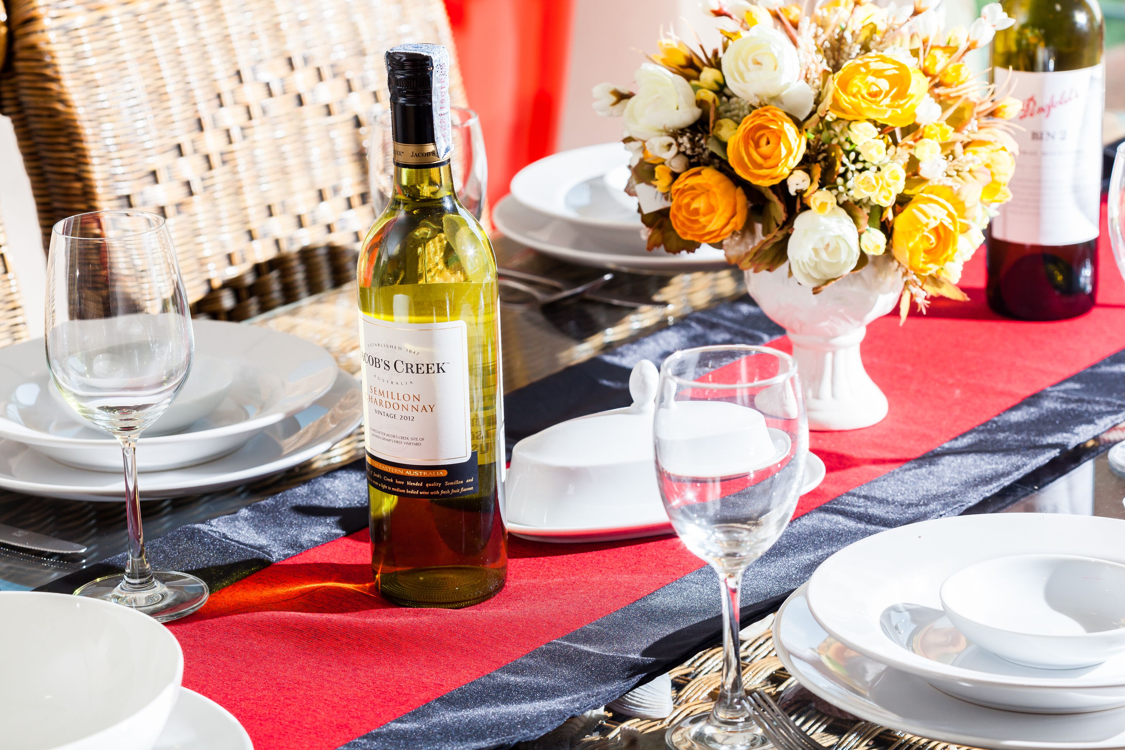 A table set for a meal with wine bottles, glasses, and a floral centerpiece.