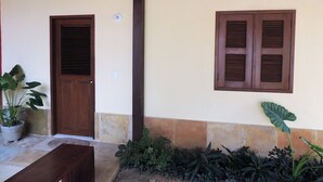 A building exterior with a wooden door, a window with shutters, and a potted plant. - Our House in Jeri 1 (Jijoca de Jericoacoara)