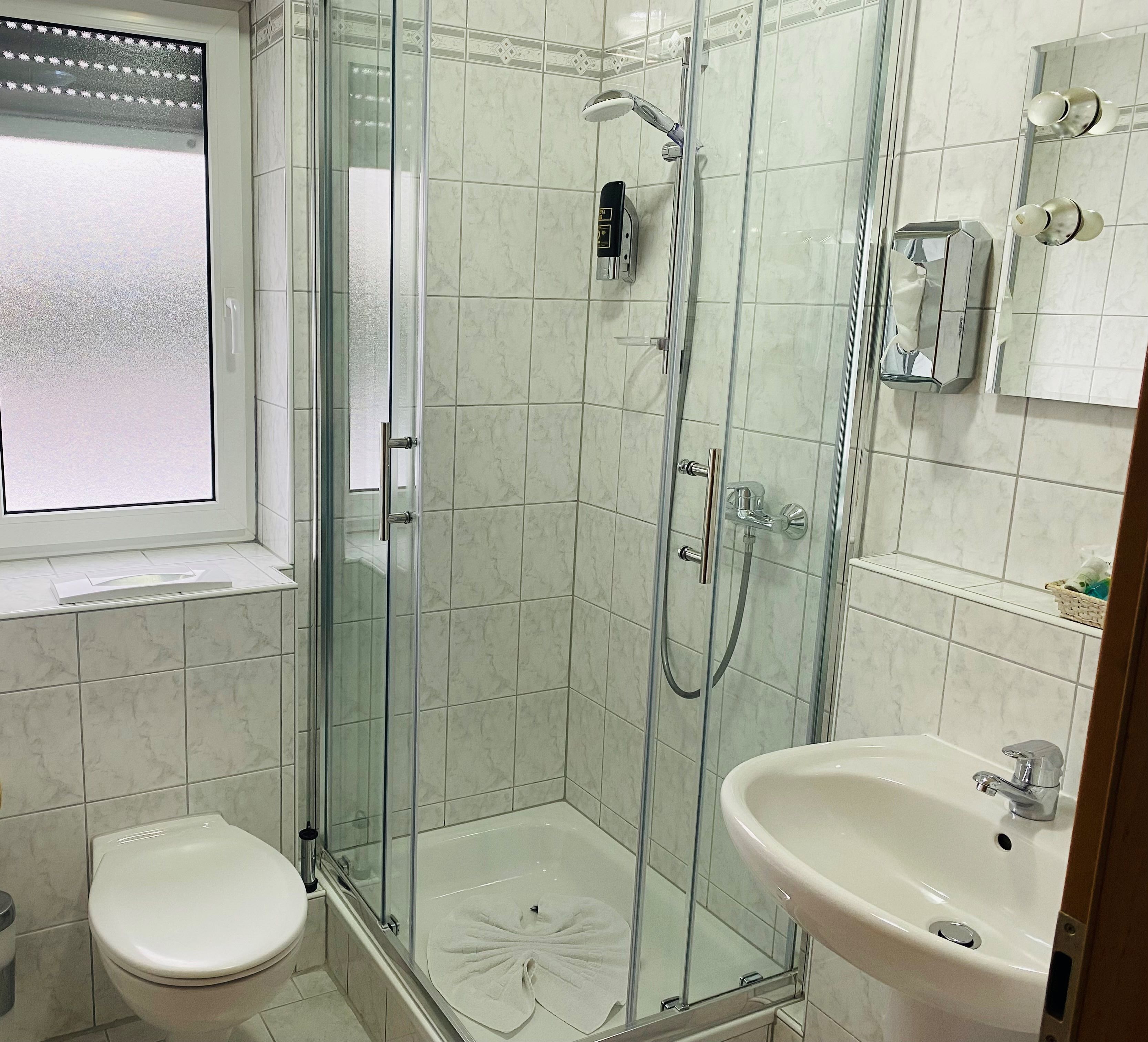 Une salle de bain avec une douche à parois de verre, des toilettes et un lavabo.