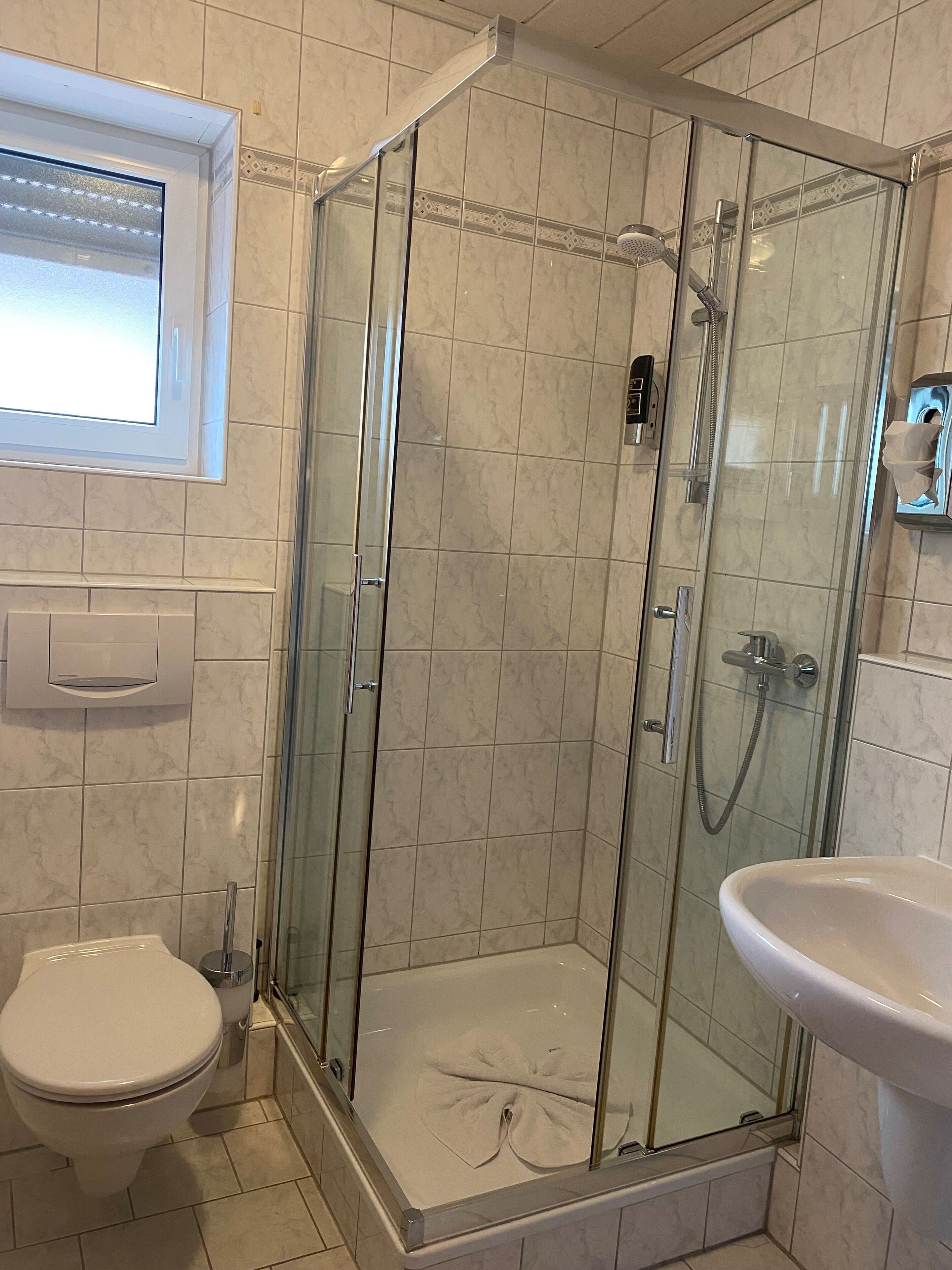 A bathroom with a glass-enclosed shower, a toilet, and a sink.
