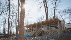 A cabin with a wooden deck, a staircase, and a view of the surrounding trees. - 2 Bedroom Lakefront Cabin with Hot Tub! (Brookport)