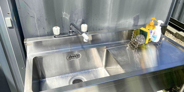A stainless steel sink with a faucet and soap dispenser.