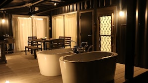 A modern bathroom with two large tubs, a wooden floor, and a table with chairs. - Rakuten STAY Villa Miyakojima (Miyakojima)