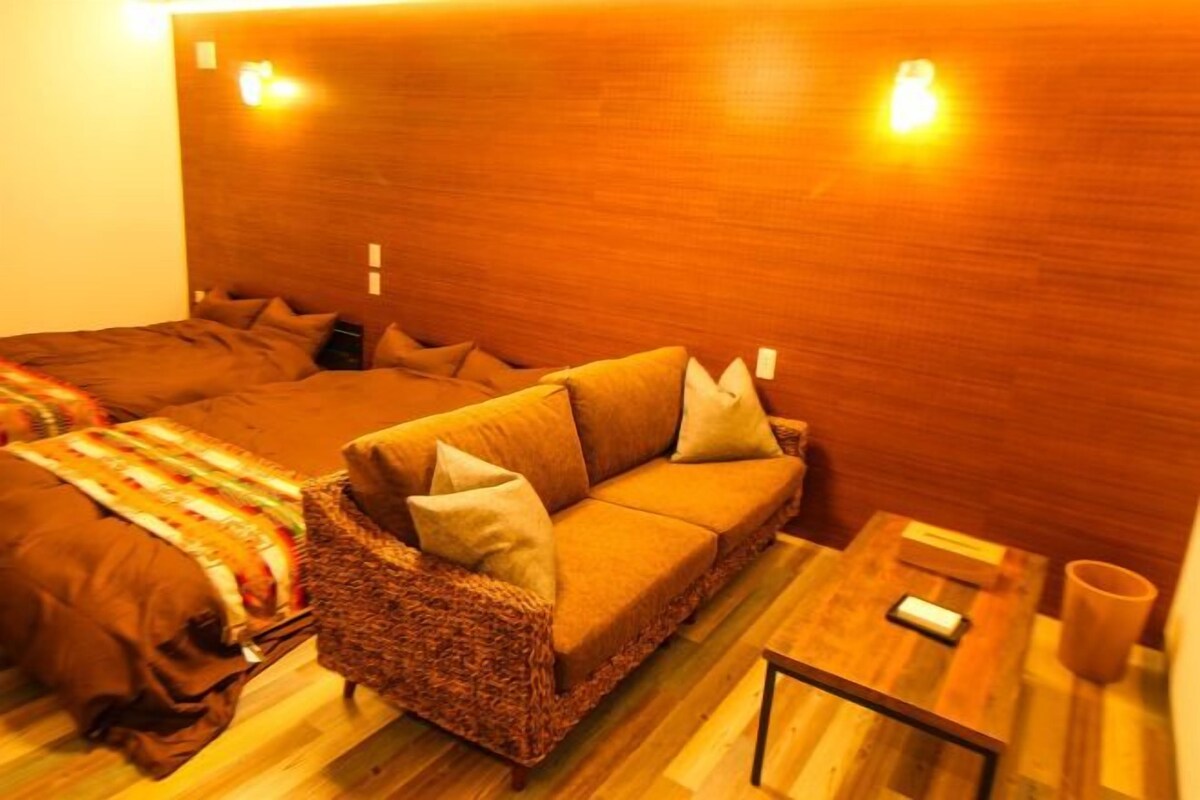 A cozy room with a brown sofa, a wicker chair, and a small wooden table with a cup.