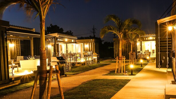 A well-lit outdoor area with a barbecue setup, palm trees, and a pathway leading to a building. - Rakuten STAY Villa Miyakojima (Miyakojima)
