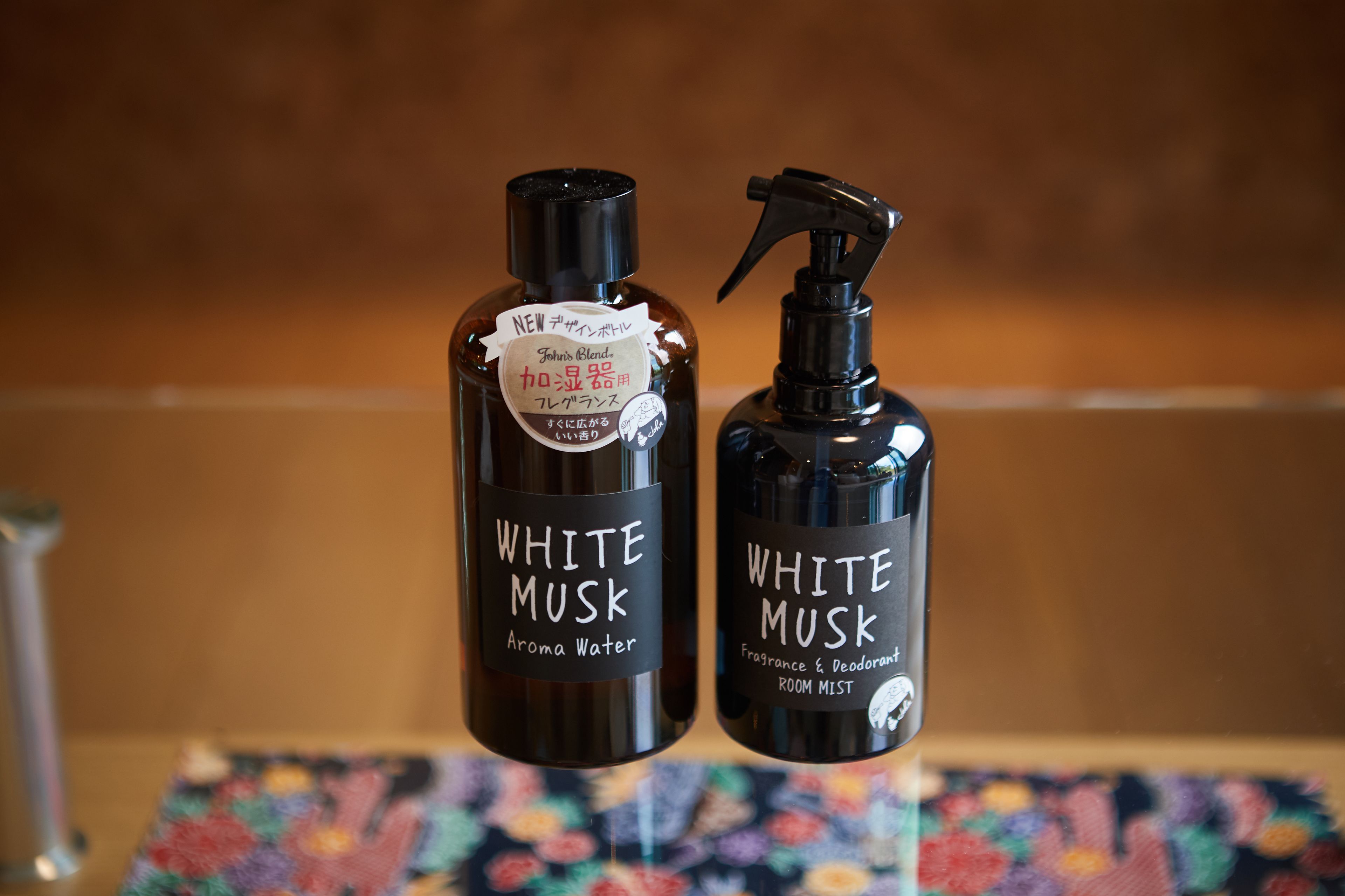 Deux flacons de produits de la gamme White Musk, dont l’un est étiqueté « Eau parfumée » et l’autre « Brume parfumée et désodorisante pour pièce ».