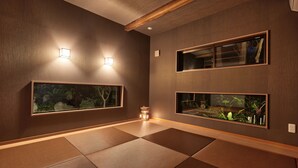 Ein Zimmer mit Tatami-Boden, zwei Wand-Aquarien und einem kleinen Tisch mit einer Lampe.