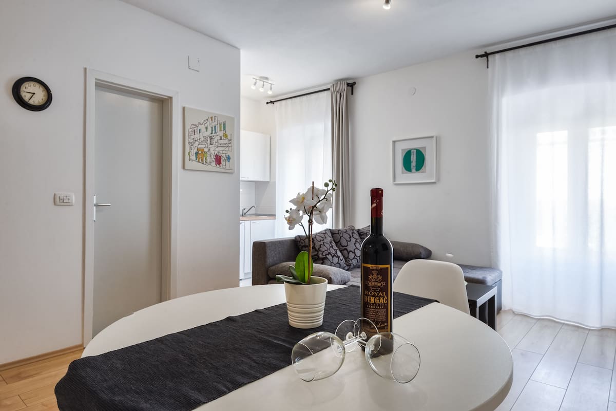 Un salon moderne avec une table à manger, une bouteille de vin et une plante en pot.
