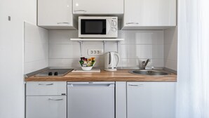 Une cuisine moderne avec des meubles blancs, un four à micro-ondes, une bouilloire et un évier.