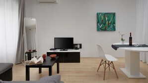 Un salon moderne avec un téléviseur à écran plat, une table à manger, une chaise blanche et un grand miroir.