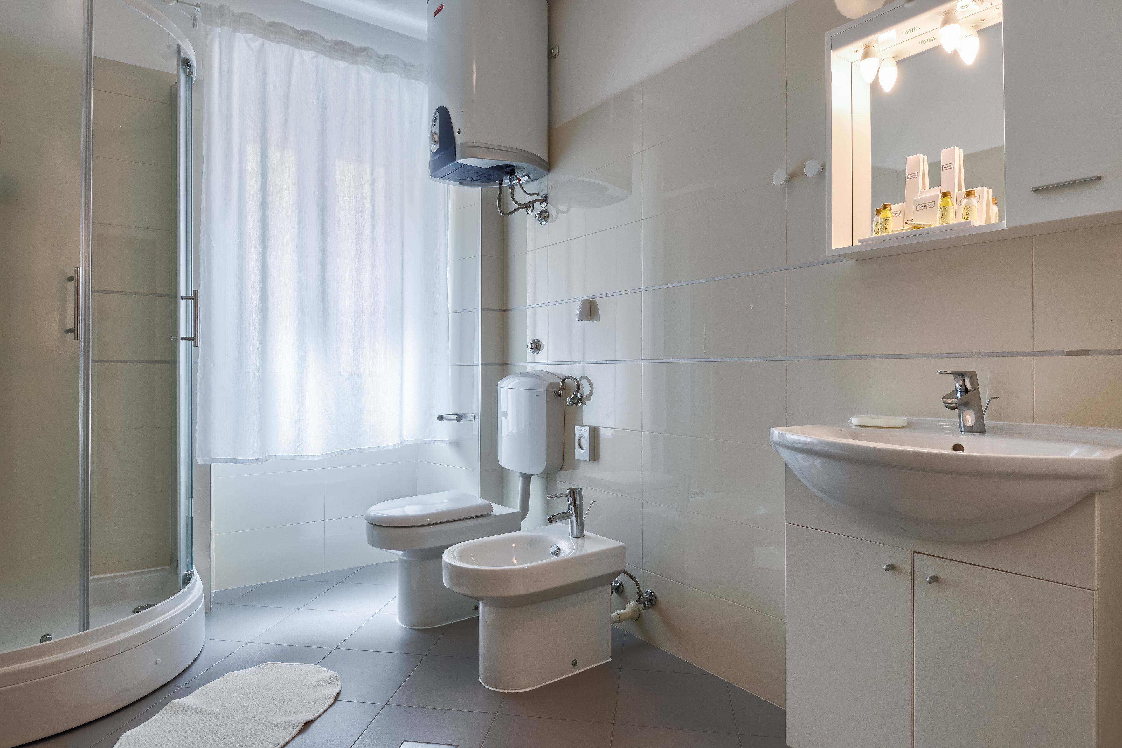 Une salle de bain moderne avec une douche à parois de verre, des toilettes, un bidet et un lavabo avec un miroir au-dessus.