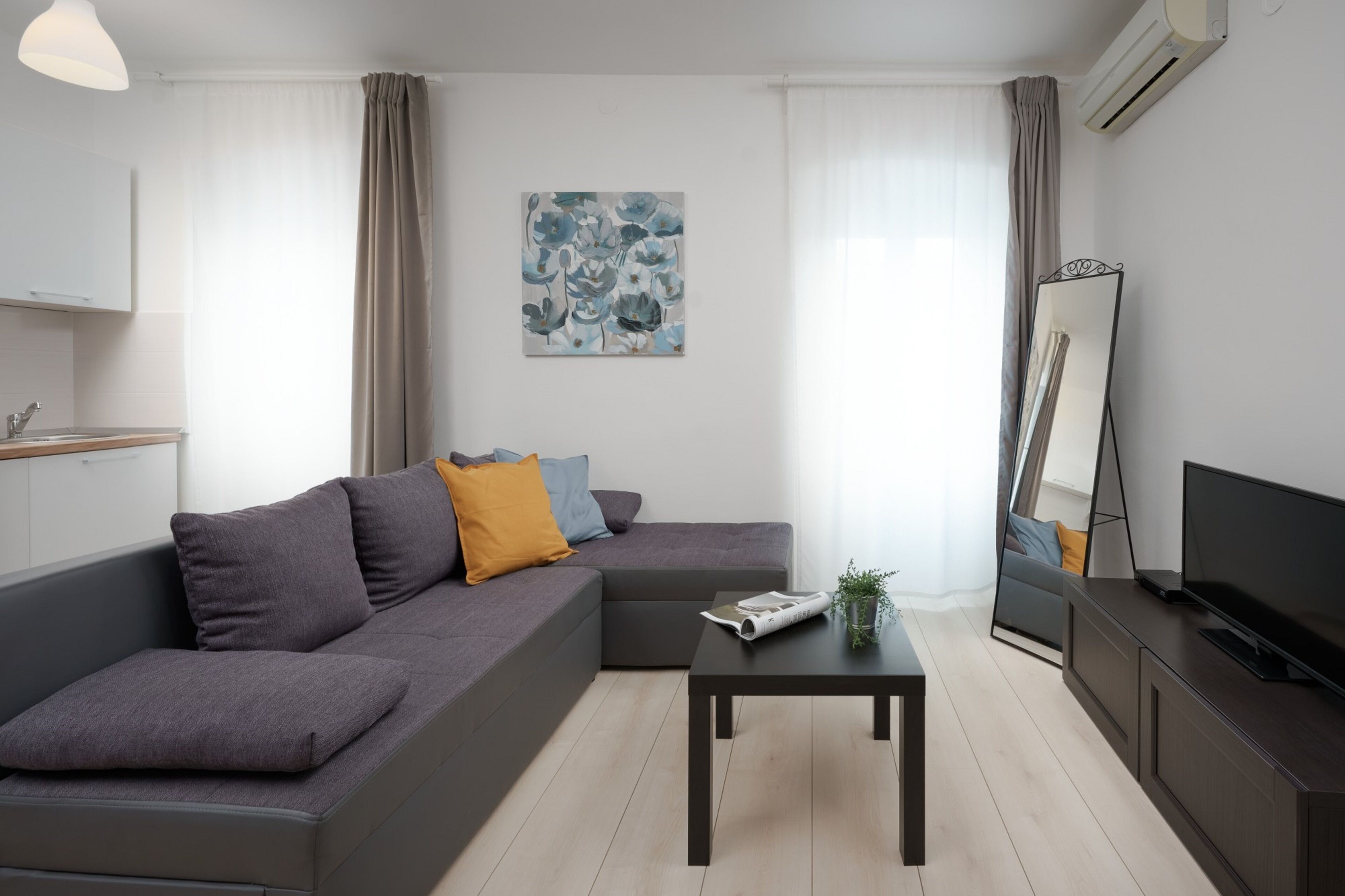 Una sala de estar moderna con un sofá gris, una mesa de centro, un televisor de pantalla plana y un cuadro en la pared.