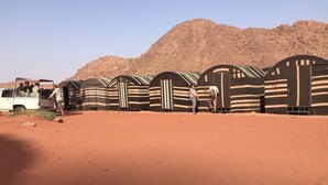 A desert landscape with tents and a Toyota vehicle. - Rum Road - Hostel (Wadi Rum)