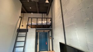 A loft-style room with a bunk bed, a ladder, a door, and a TV. - Campus Community A-Hotel (Kyiv)