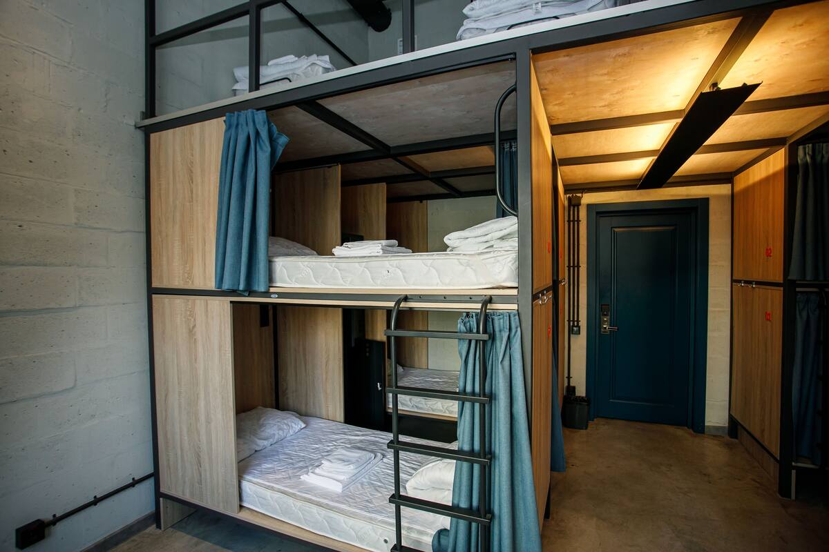 A bunk bed room with a wooden ladder, a door, and a small closet.