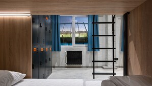 A hotel room with a bed, a ladder, a view of a bridge, and a set of lockers. - Campus Community A-Hotel (Kyiv)