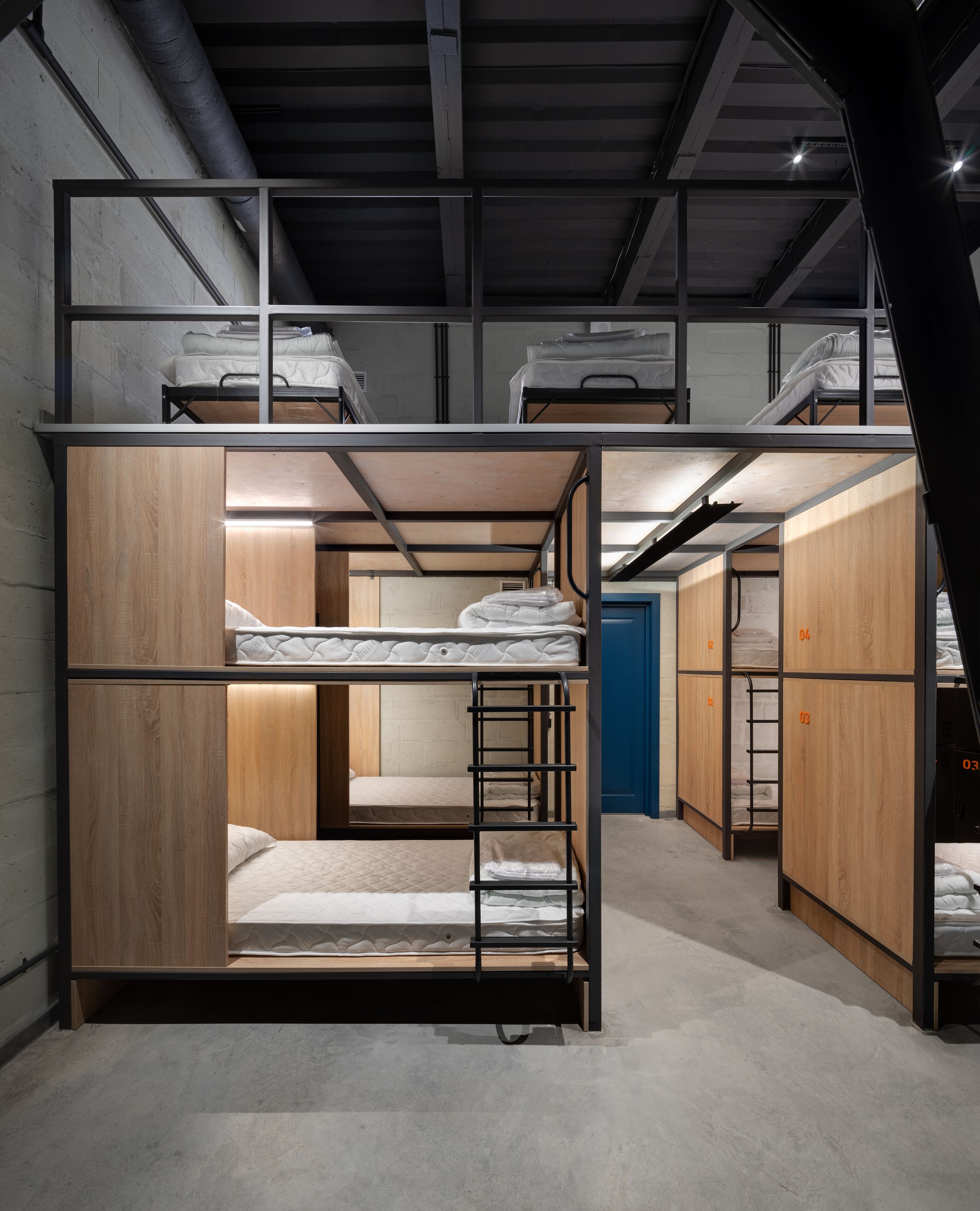 A bunk bed room with a wooden interior, a blue door, and a ladder.