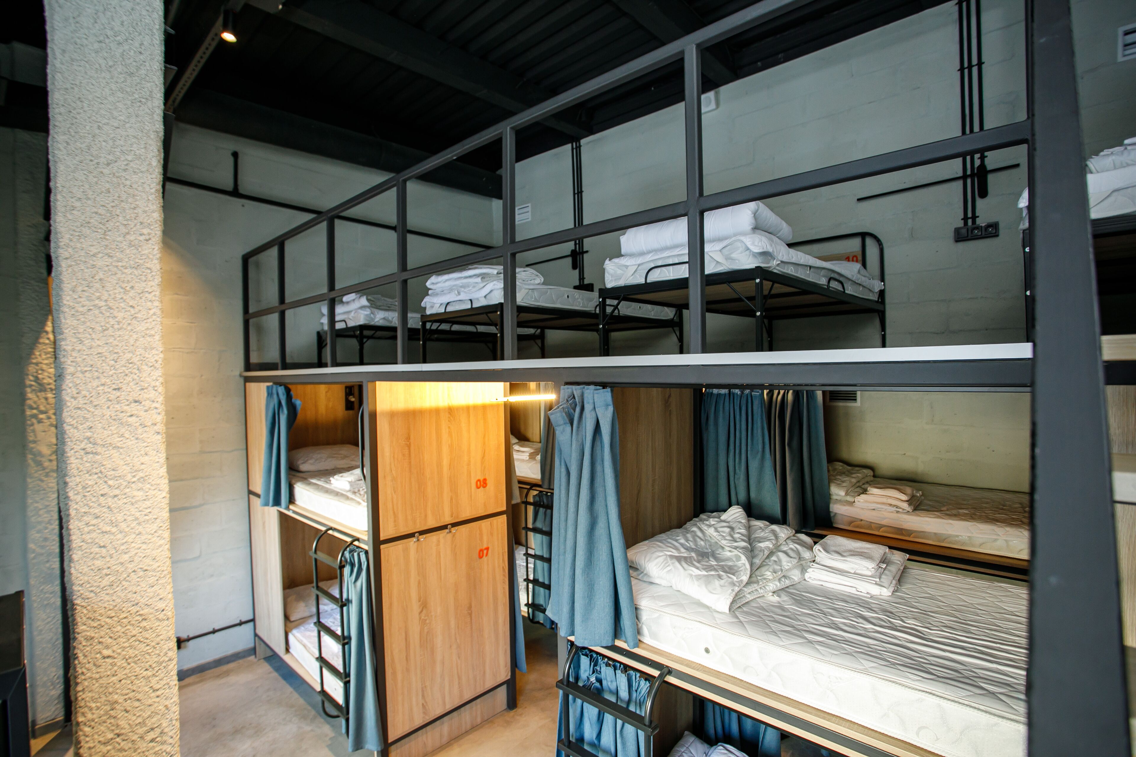 A dormitory-style room with bunk beds, wooden lockers, and curtains.
