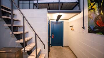 A narrow hallway with a wooden staircase leading to a bunk bed area.