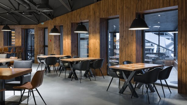 A modern interior with wooden panel walls, black pendant lighting, and a mix of wooden and metal tables and chairs. - Campus Community A-Hotel (Kyiv)