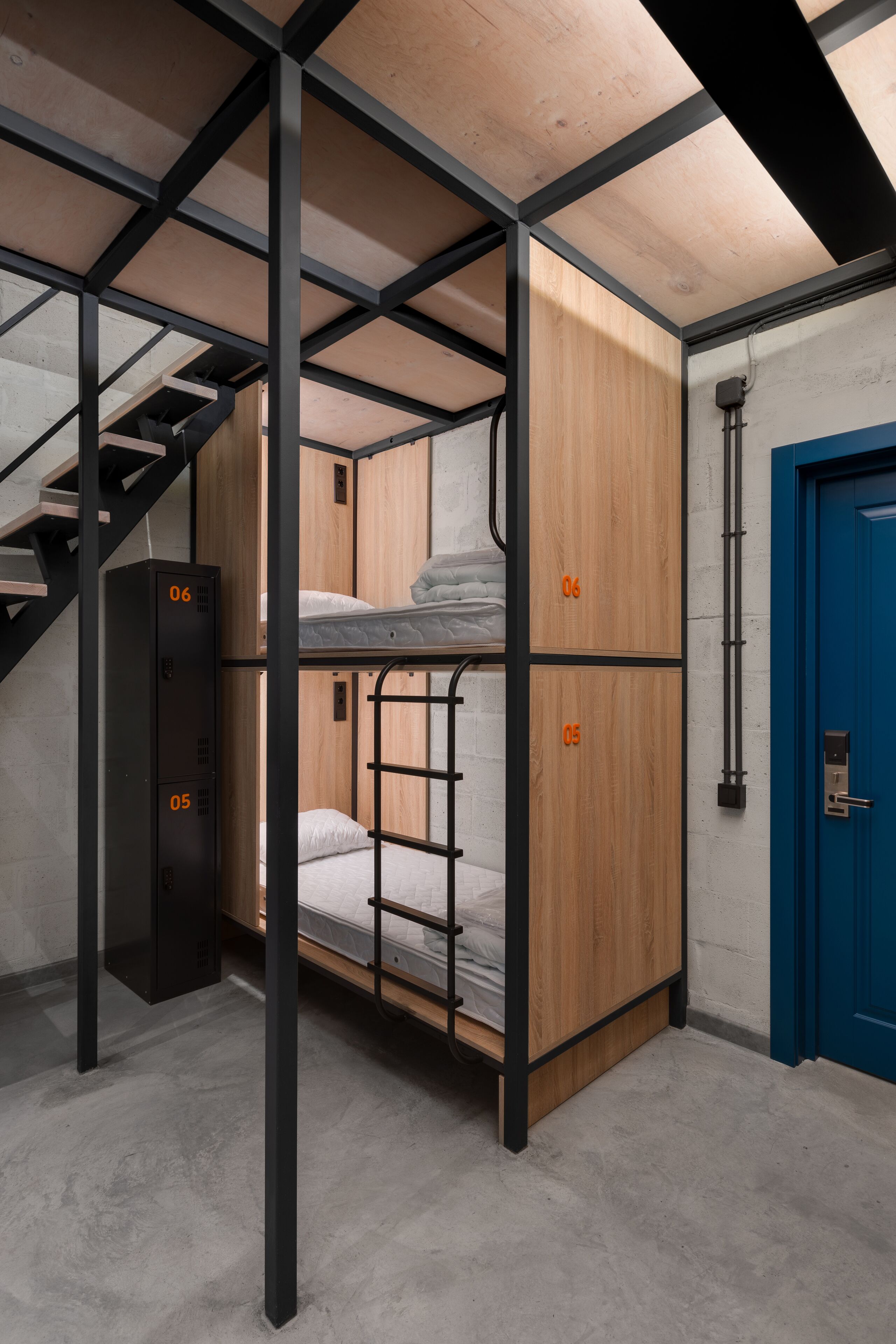 A bunk bed room with a staircase, a blue door, and a black cabinet with numbers on it.