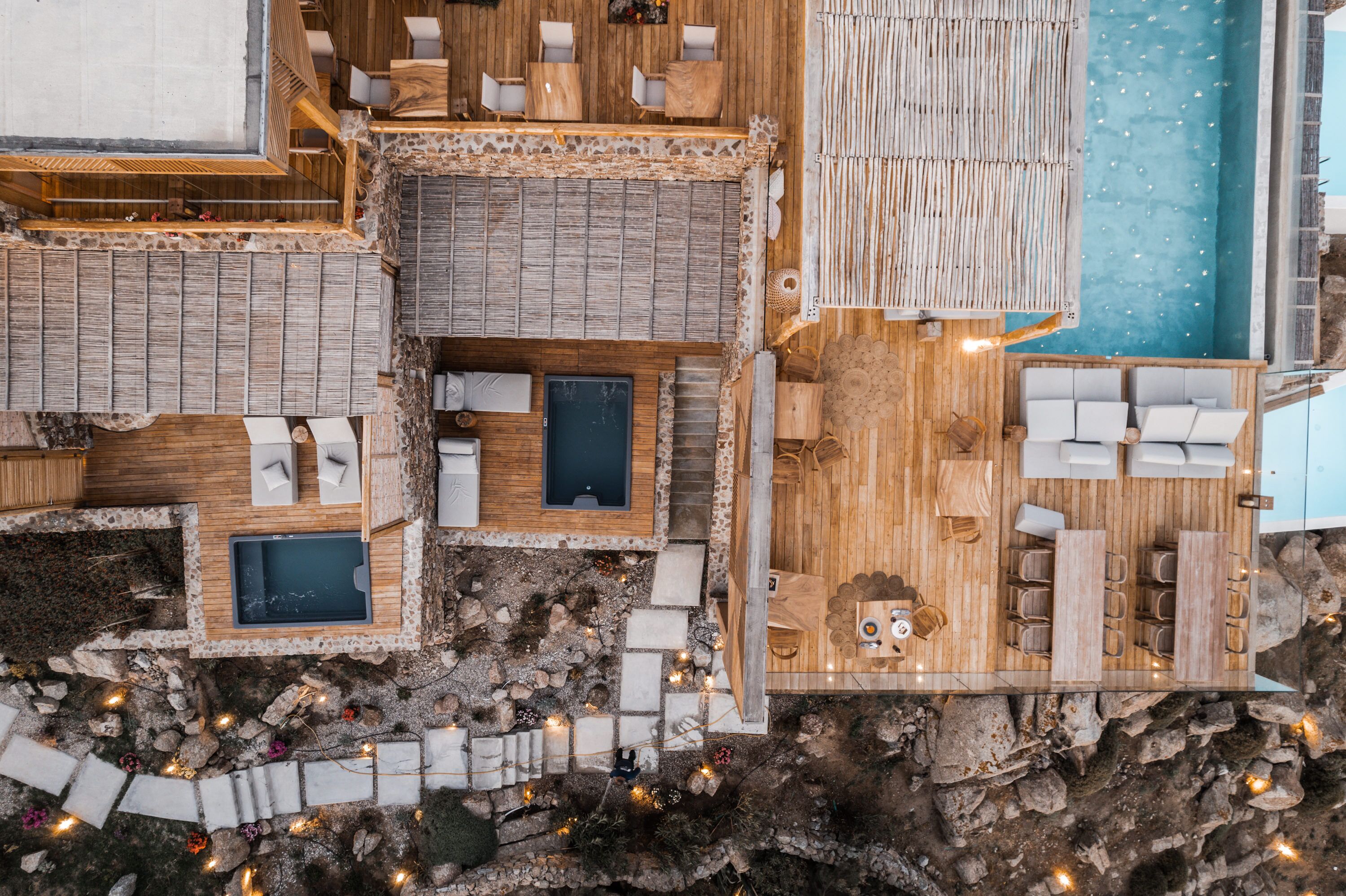 A rooftop terrace with wooden flooring, multiple seating areas, and a pool.