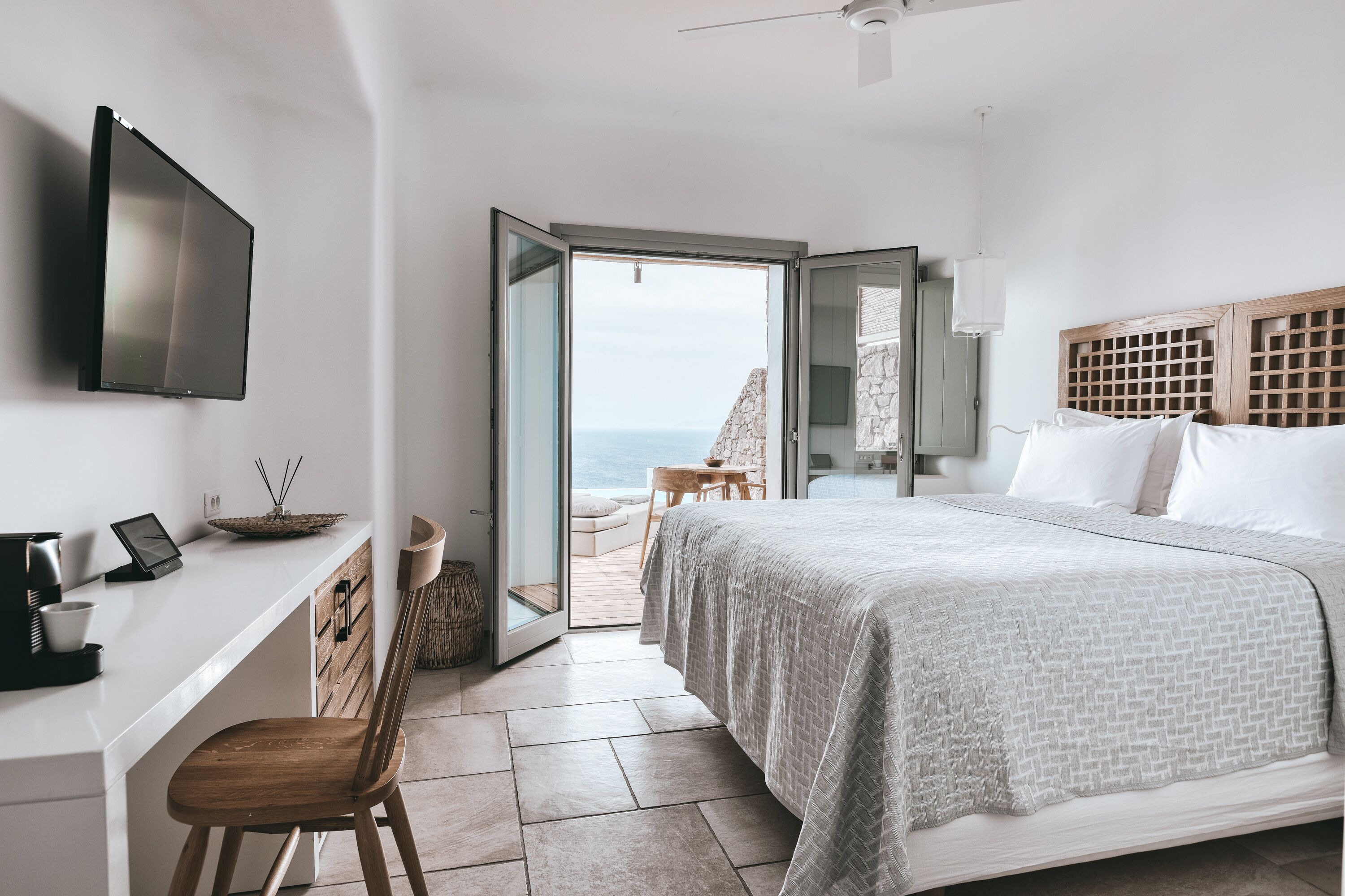 Ein Schlafzimmer mit einem Bett, einem Schreibtisch, einem Sessel und einem Fernseher.