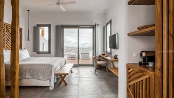 A modern bedroom with a bed, desk, and a view of the outdoors.