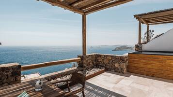 A wooden deck with a stone wall and a view of the sea.