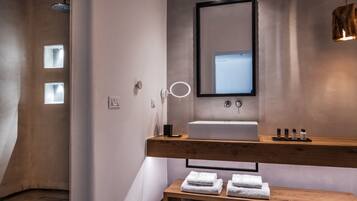 Une salle de bain moderne avec un meuble-lavabo en bois, un grand miroir et un banc avec des serviettes.