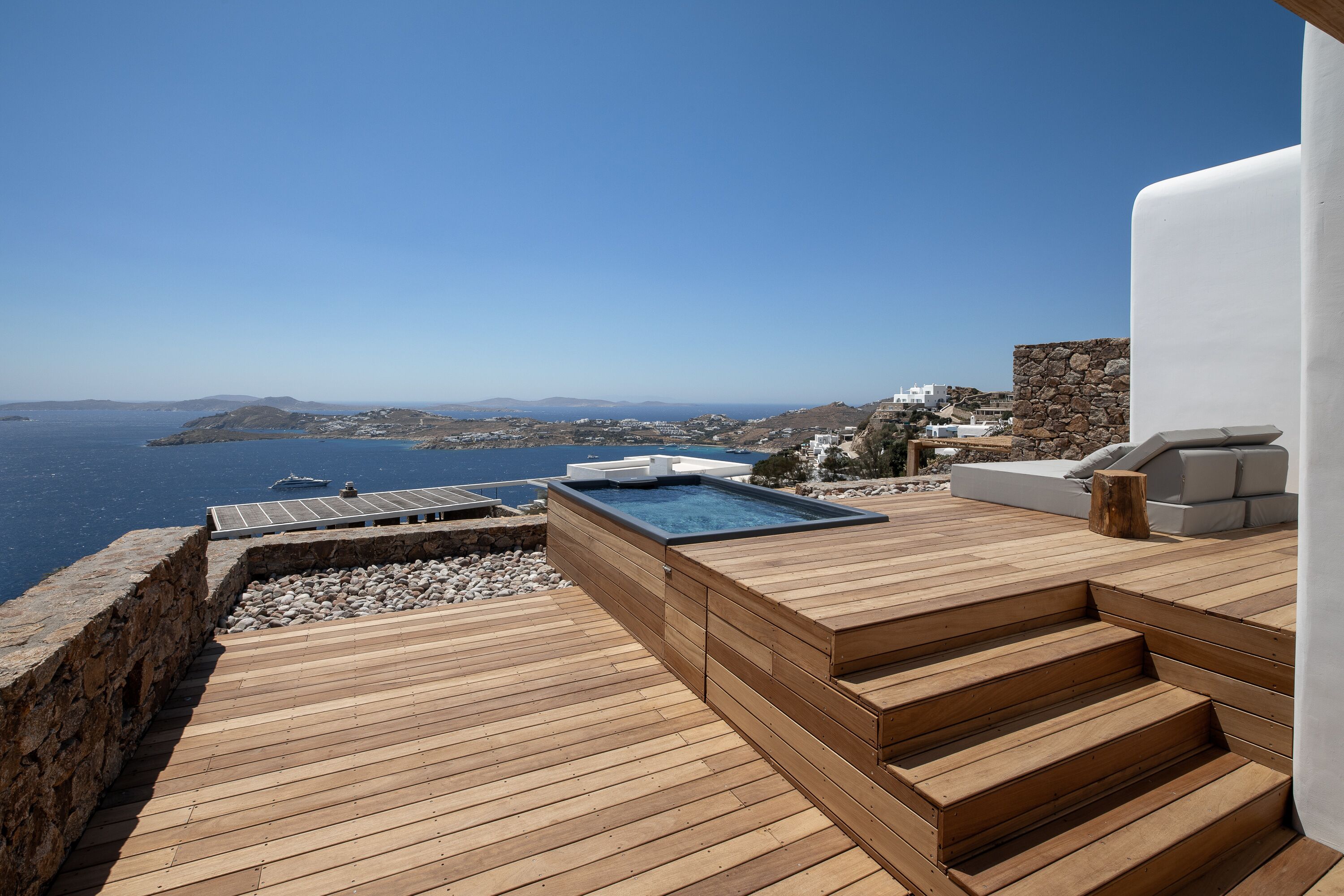 A wooden deck with a hot tub and a view of the sea.