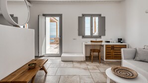 A modern, minimalist living room with a wooden bench, a white table, and a grey sofa. - Alissachni Mykonos (Mykonos)