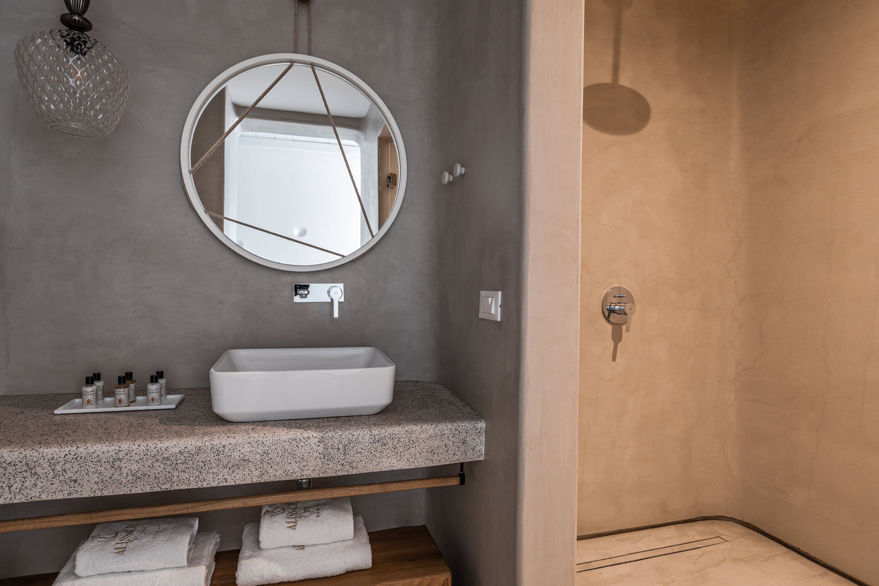 A bathroom with a white sink, a round mirror, and a shower area.