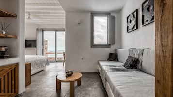 A modern room with a bed, a sofa, a small table, and a window.