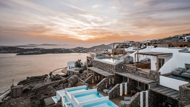 A resort with a pool, outdoor seating, and a view of the sea at sunset. - Alissachni Mykonos (Mykonos)