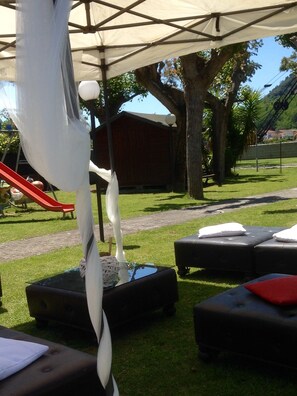 An outdoor seating area with black cushioned benches and a white canopy overhead. - Albergo Locanda Maria (Ameglia)